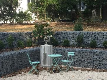 A couple of chairs and tables in the middle of a garden.