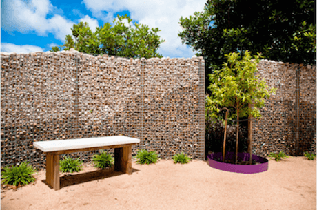 a Gabion Fence, trees, and a bench