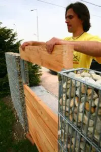 a man installing a wooden plate for the fence